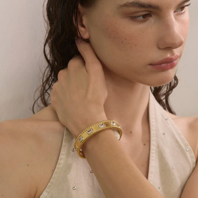 Woman wearing a gold bracelet with a neutral background