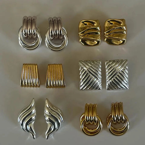 Collection of gold and silver earrings on a light gray background
