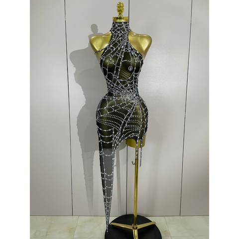 Black dress with silver embellishments on a gold mannequin against a white wall.