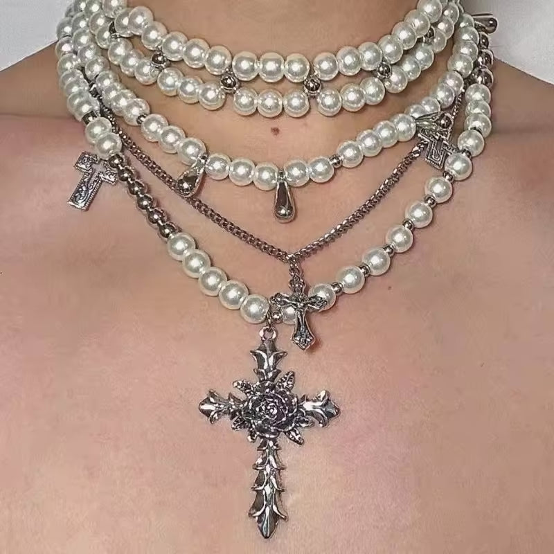 Multiple pearl necklaces with silver crosses on a person's chest.