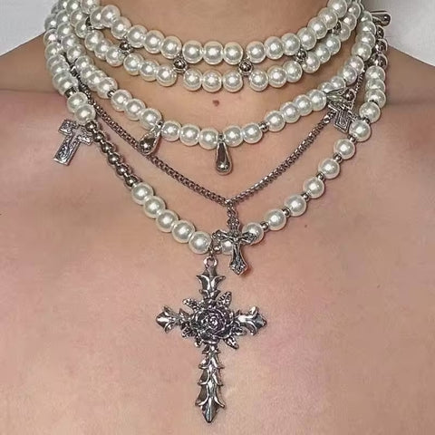 Multiple pearl necklaces with silver crosses on a person's chest.