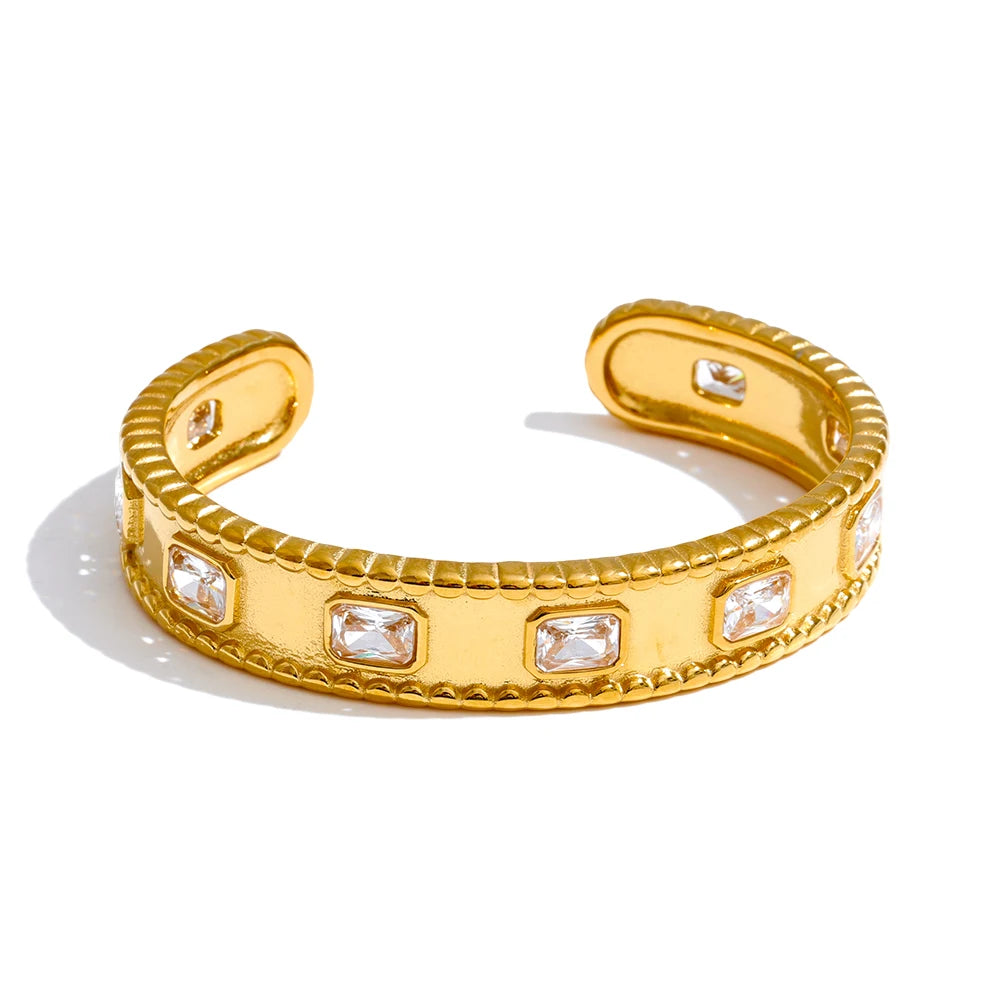 Gold open cuff bracelet with embedded crystals on a white background