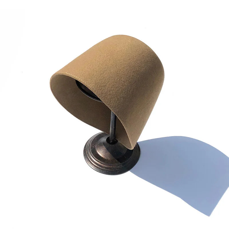 Brown felt hat on a stand with a white background